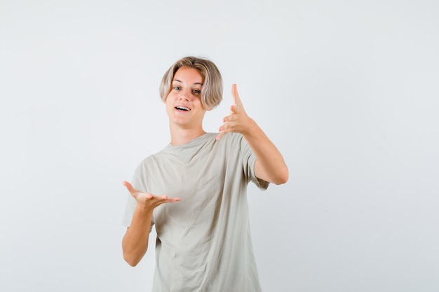 Jonge tiener jongen in t-shirt handen uitrekken op camera en op zoek gelukkig, vooraanzicht.