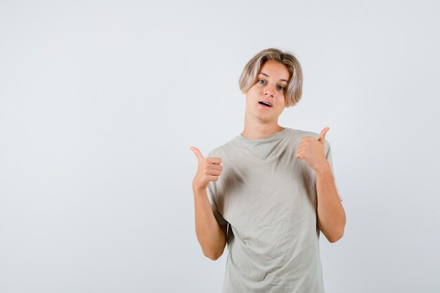 Jonge tienerjongen in t-shirt met dubbele duimen omhoog en tevreden, vooraanzicht.