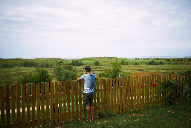 Jonge toerist die groen landschap bekijkt dat zich een omheining bevindt