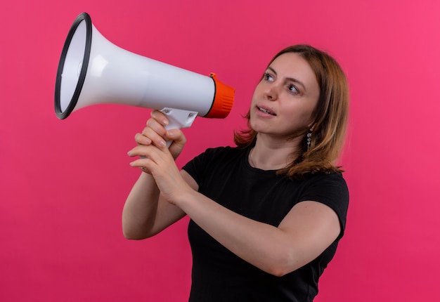 Jonge toevallige vrouw die door spreker spreekt die naar linkerkant op geïsoleerde roze muur kijkt