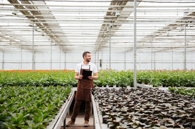 Jonge tuinman die met installaties in serre werkt