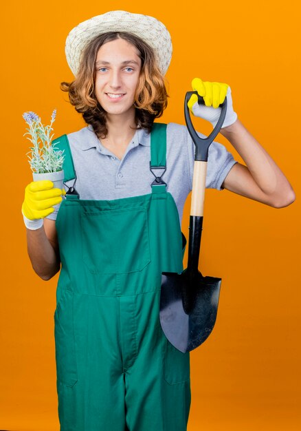 Jonge tuinman man in rubberen handschoenen dragen jumpsuit en hoed met schop