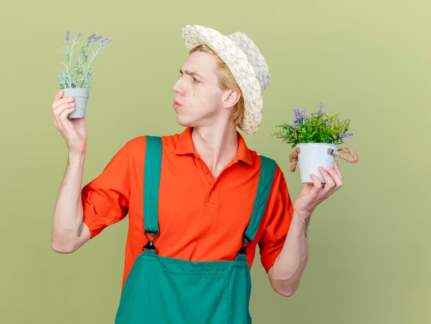 Jonge tuinman man met jumpsuit en hoed met potplanten