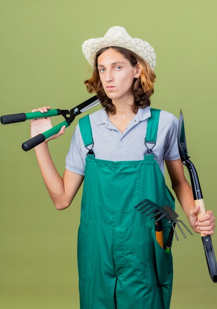 Jonge tuinman man met jumpsuit en hoed met tuingereedschap