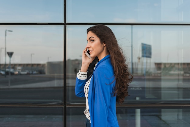 Jonge uitvoerende praten over de telefoon met glazen gebouw achtergrond