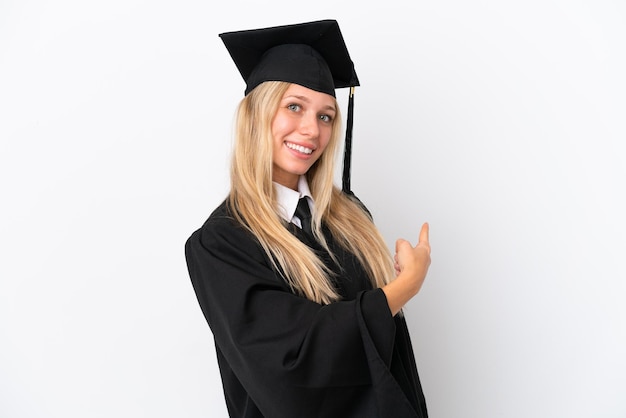 Jonge, universitair afgestudeerde blanke vrouw geïsoleerd op een witte achtergrond die terug wijst Premium Foto