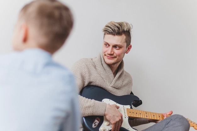 Jonge vader met gitaar naar de kant kijken