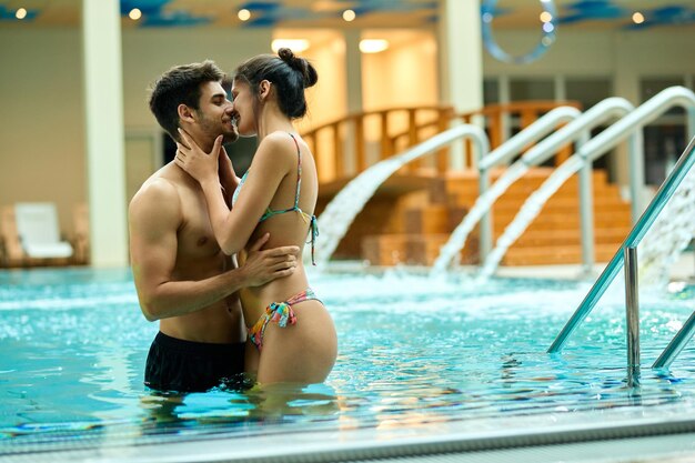 Jonge verliefde paar zoenen terwijl ze in het zwembad zijn in het wellnesscentrum