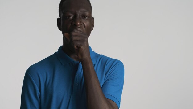 Jonge verveelde Afro-Amerikaanse man geeuwen en die betrekking hebben op de mond met de hand geïsoleerd op een witte achtergrond Saai expression