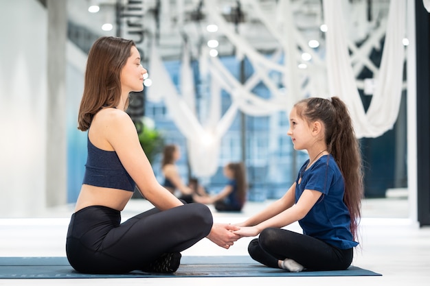 Jonge volwassen moeder en dochtertje samen beoefenen van yoga