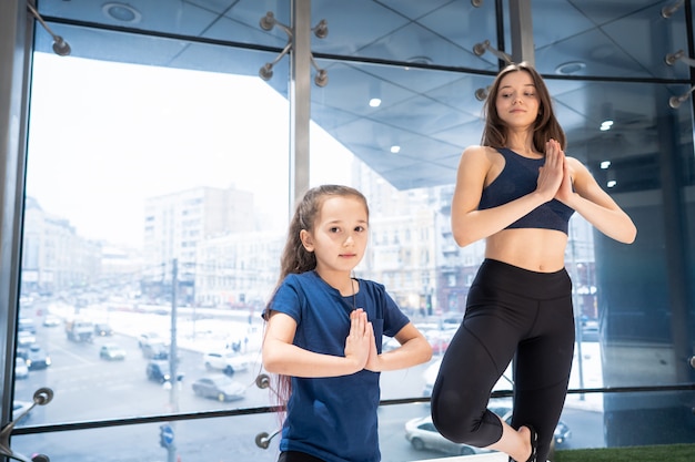 Jonge volwassen moeder en dochtertje samen beoefenen van yoga