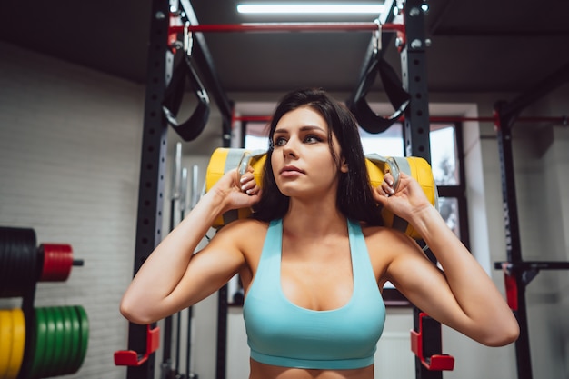 Jonge volwassen vrouw die krachtoefeningen in de gymnastiek doet