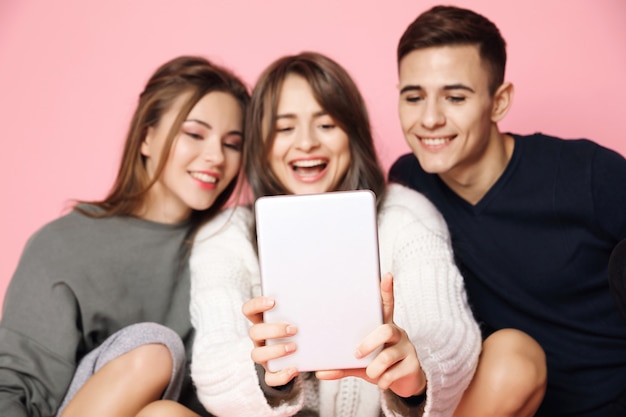 Jonge vrienden maken selfie op tablet op roze