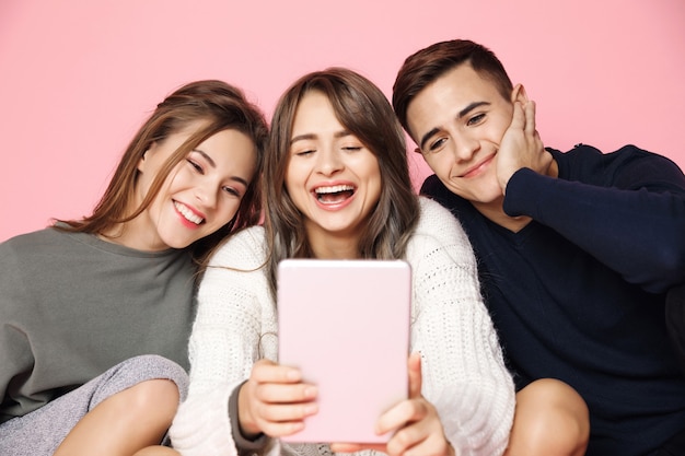 Jonge vrienden maken selfie op tablet op roze