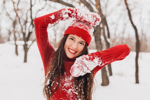 Jonge vrij opgewonden spontane lachende gelukkige vrouw in rode wanten en muts dragen gebreide trui wandelen spelen in het park in de sneeuw, warme kleren, plezier