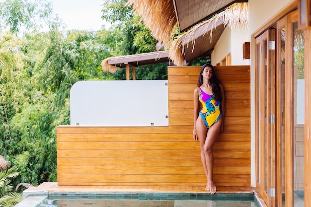 Jonge vrij positieve gelukkig slanke vrouw in kleurrijke zwembroek in geweldige luxe hotelvilla genieten van mooie dag op vakantie in Thailand
