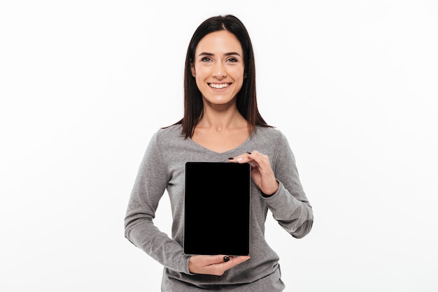 Jonge vrolijke dame die vertoning van tabletcomputer toont.