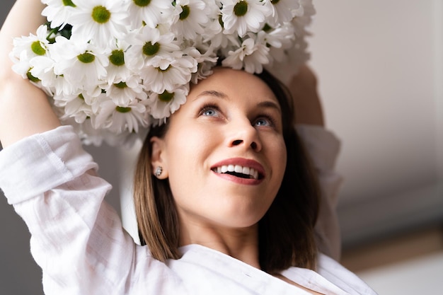 Jonge, vrolijke, lieve, mooie lachende vrouw geniet van een boeket witte verse bloemen