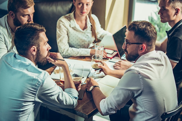 Jonge vrolijke mensen glimlachen en gebaar terwijl u ontspant in pub.