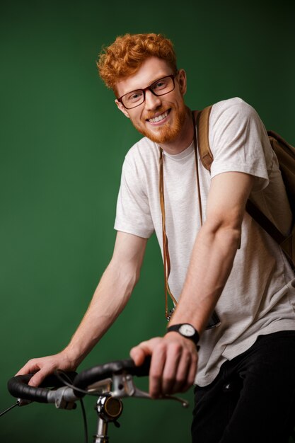 Jonge vrolijke readhead bebaarde hipster met rugzak en retro camera, klaar om te fietsen