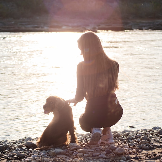 Gratis foto jonge vrouw aan het meer met haar hond