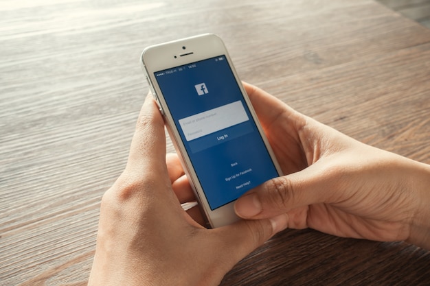 Jonge vrouw aanraakt Facebook iconen op smartphone