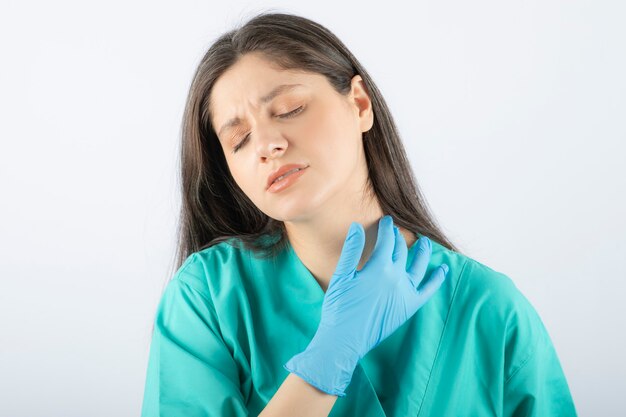 jonge vrouw arts in groen uniform aanraken van haar nek.