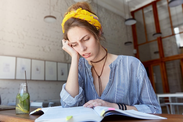 Gratis foto jonge vrouw bandana dragen en studeren in café