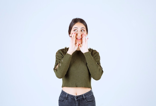 Jonge vrouw belt voor iemand op een witte achtergrond.