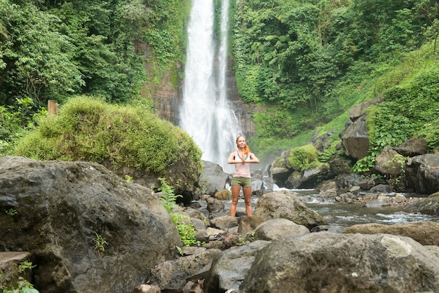 Jonge vrouw beoefenen van yoga bij de waterval