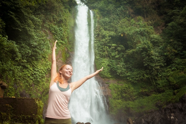 Gratis foto jonge vrouw beoefenen van yoga bij de waterval