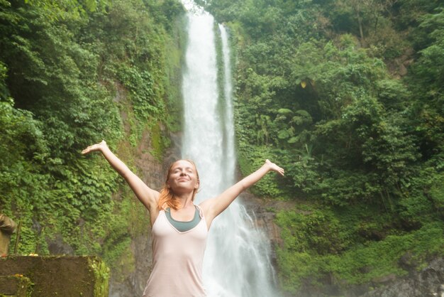 Jonge vrouw beoefenen van yoga bij de waterval