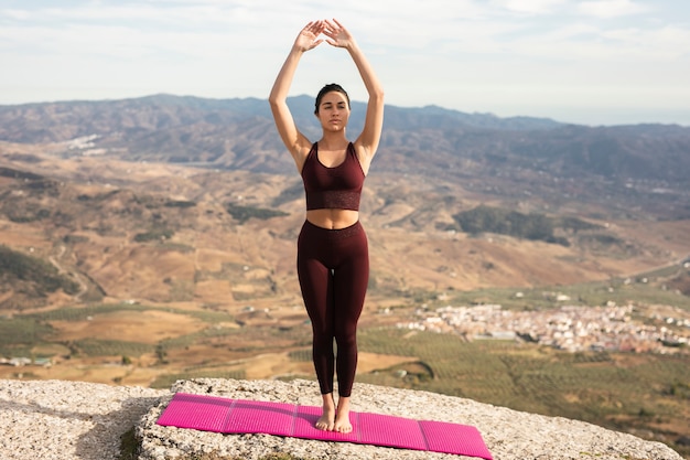 Jonge vrouw beoefenen van yoga op bergtop