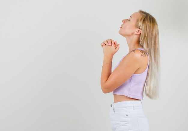 Jonge vrouw bidden met gevouwen handen in singlet