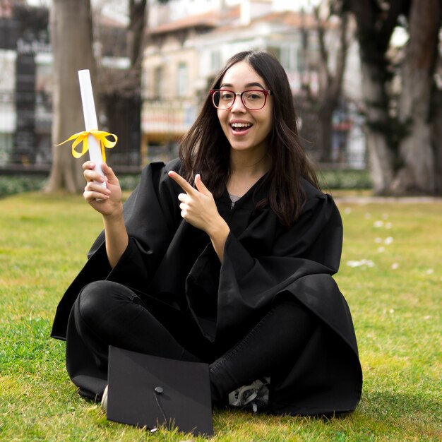 Jonge vrouw bij diploma-uitreiking die aan haar diploma richt