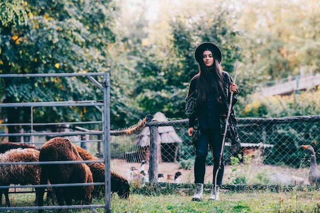 Gratis foto jonge vrouw bij een hok met schapen op een boerderij