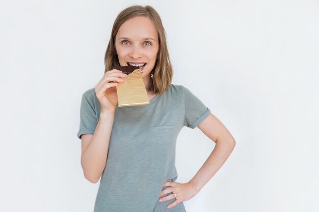 Jonge vrouw bijten chocoladereep in bladgoud