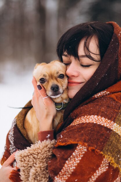 Jonge vrouw buiten het park met haar kleine hond in de winter