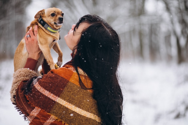 Jonge vrouw buiten het park met haar kleine hond in de winter