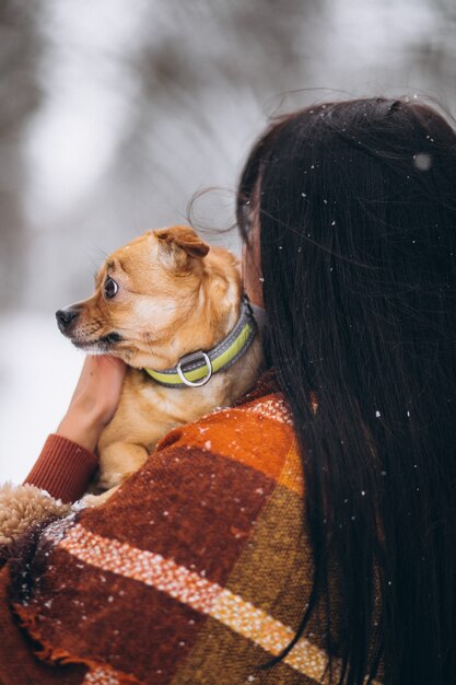 Jonge vrouw buiten het park met haar kleine hond in de winter