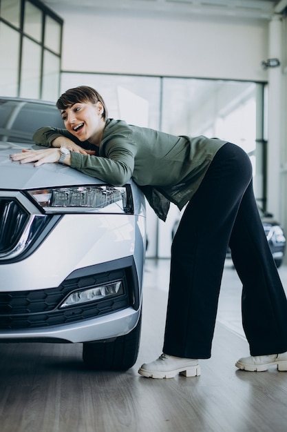Jonge vrouw choosimng een auto in een autoshowroom