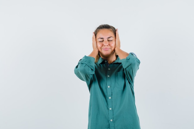 Jonge vrouw clasping hoofd met handen in blauw shirt en op zoek verveeld