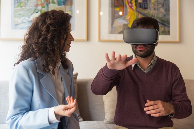 Jonge vrouw die aan de mens in VR-glazen spreekt wat betreft lucht