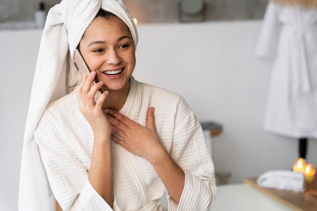 Jonge vrouw die aan de telefoon praat voordat ze een bad neemt