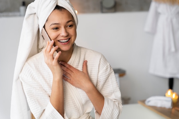 Jonge vrouw die aan de telefoon praat voordat ze een bad neemt