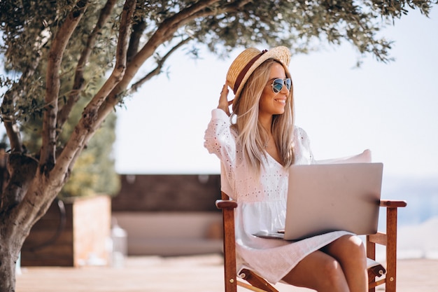 Jonge vrouw die aan laptop op een vakantie werkt