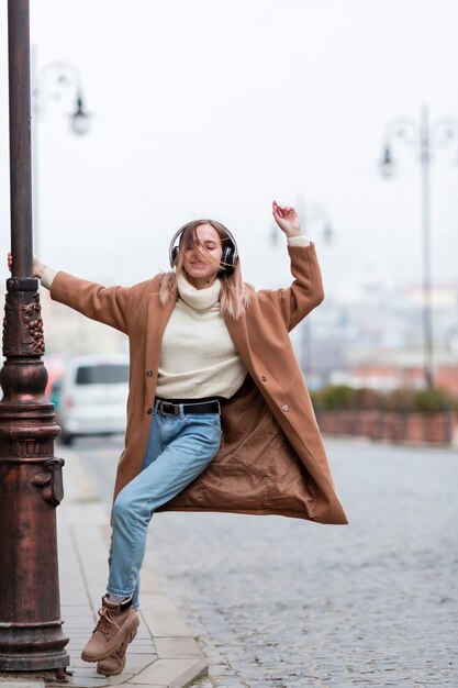 Jonge vrouw die aan muziek op hoofdtelefoons in de stad luistert