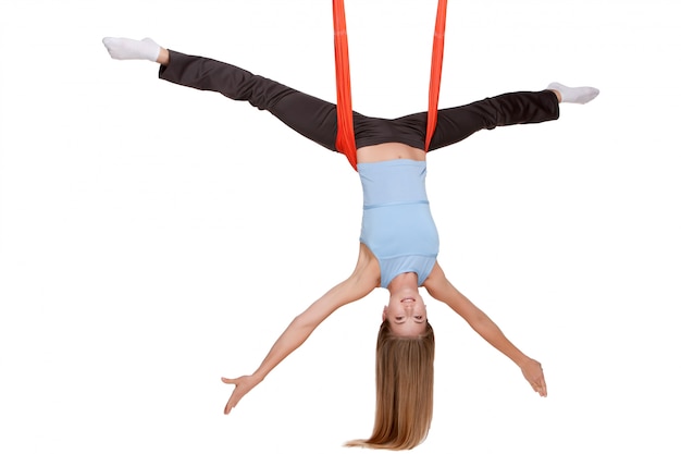 Jonge vrouw die antigravity yogaoefeningen in het uitrekken van streng maken