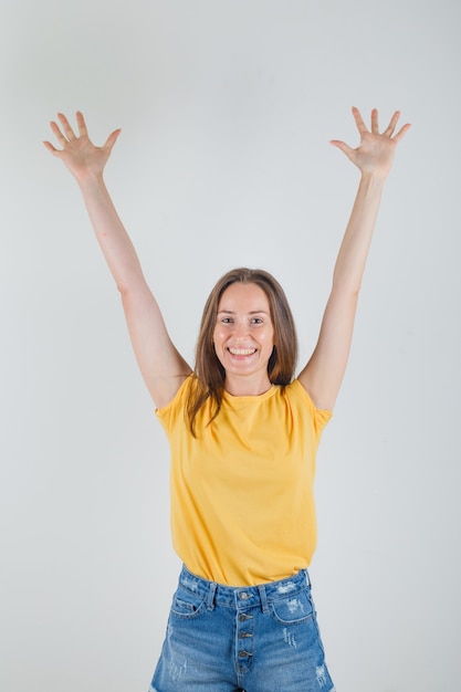 Gratis foto jonge vrouw die armen en handpalmen in t-shirt, korte broek opheft en energiek kijkt