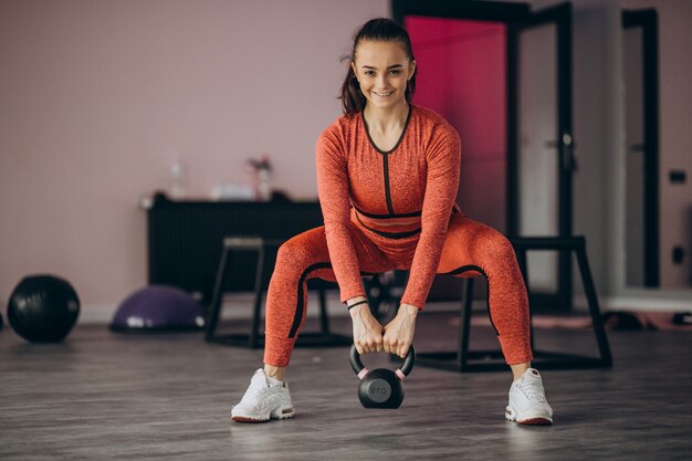 Jonge vrouw die bij de gymnastiek met gewicht uitoefent